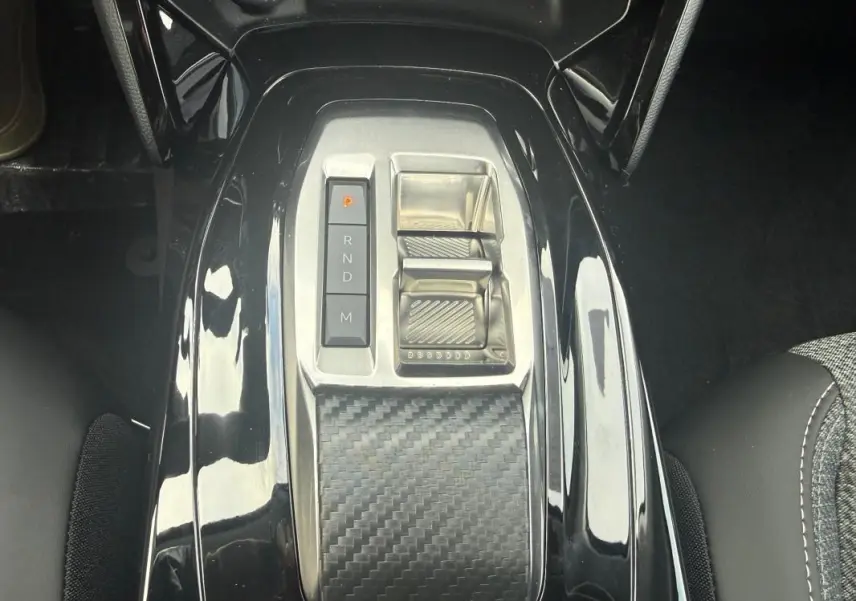 Vue rapprochée de la console centrale noire brillante avec sélecteur de vitesses automatique du Peugeot 208 Hybrid 145 gris.