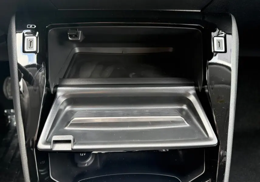 Gros plan sur le rangement central ouvert de la Peugeot 208 Hybrid 145 gris, avec ports USB visibles de chaque côté.