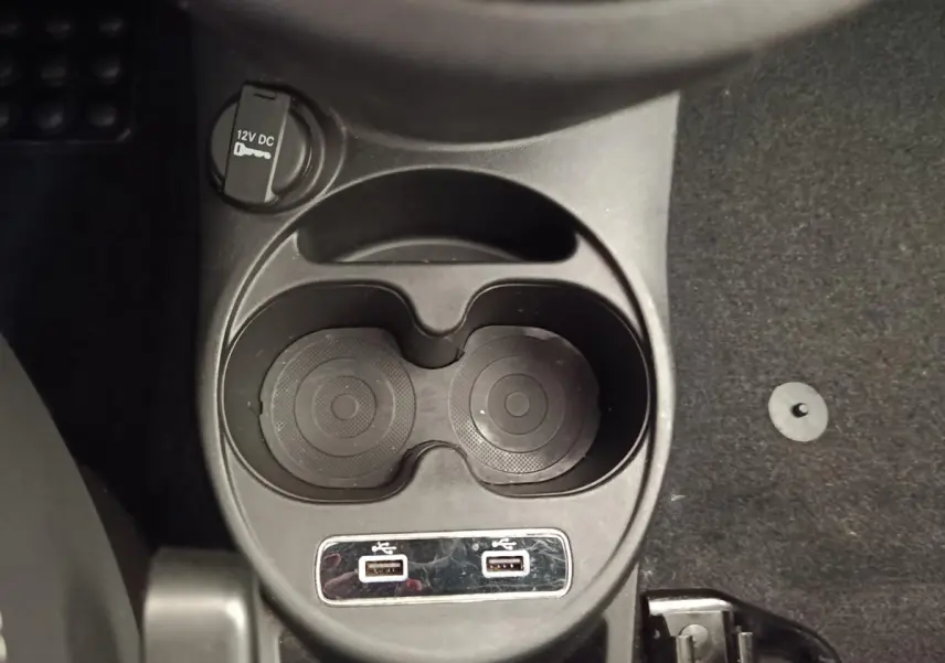Vue rapprochée de la console centrale noire avec porte-gobelets et deux ports USB de la Fiat 500 Dolcevita blanche.
