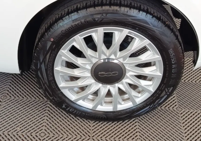 Gros plan sur la roue avant droite blanche d’une FIAT 500 Hybrid avec jante argentée et logo central noir.