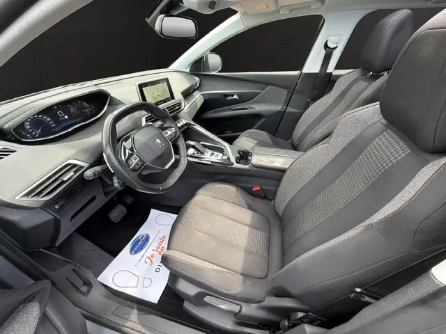 Vue intérieure côté gauche de la Peugeot 208 gris platinium, sièges tissu noirs et volant cuir multifonctions.