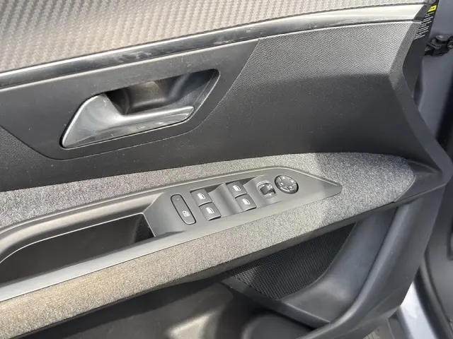Gros plan sur la poignée intérieure et les commandes de porte côté conducteur de la Peugeot 208 gris platinium.