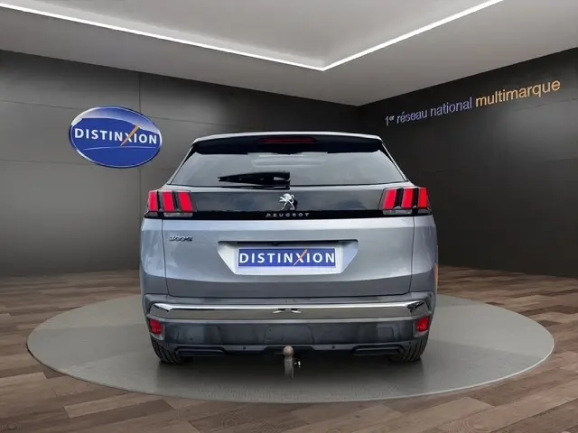 Vue arrière d'une Peugeot 208 gris platinium 2017 dans un showroom avec logo Distinxion en arrière-plan.