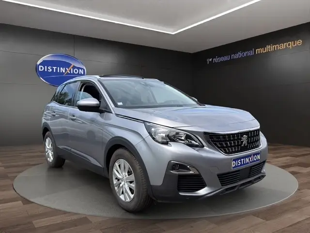 Peugeot 208 gris platinium vue 3/4 avant droit, avec rétroviseurs chromés et feux LED, en showroom.