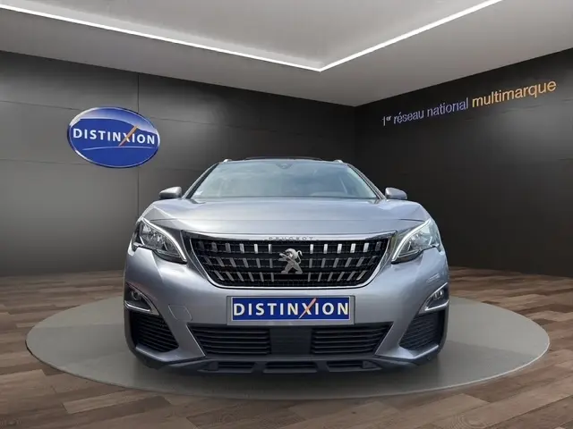 Vue avant d'une Peugeot 208 gris platinium exposée en showroom avec logo Distinxion sur fond noir.