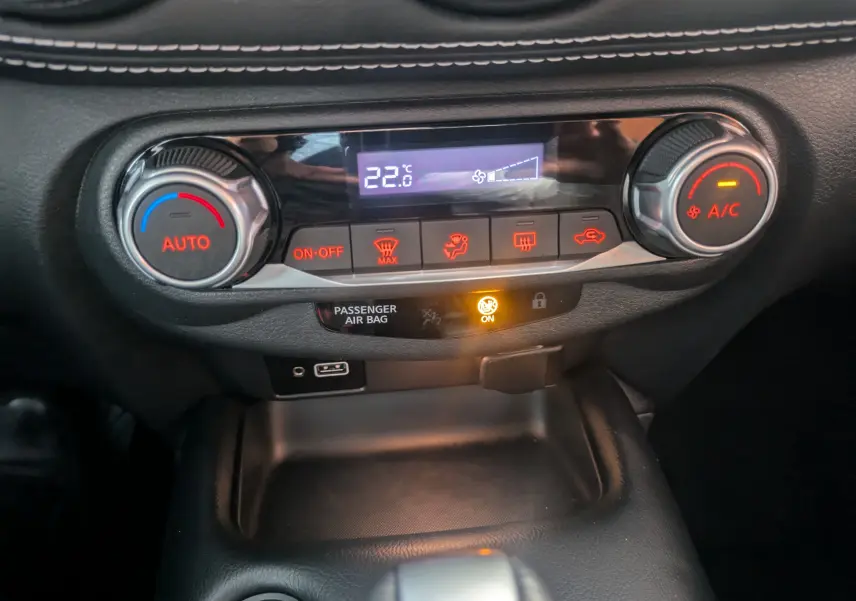 Tableau de bord du Nissan Juke 2024, zoom sur la commande de climatisation automatique affichant 22°C, boutons rétroéclairés rouges.
