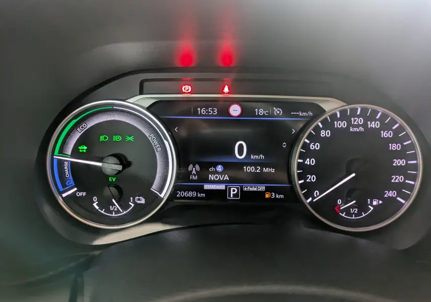 Tableau de bord numérique du Nissan Juke 2024 hybride, affichant vitesse à 0 km/h et indicateurs de charge et carburant.