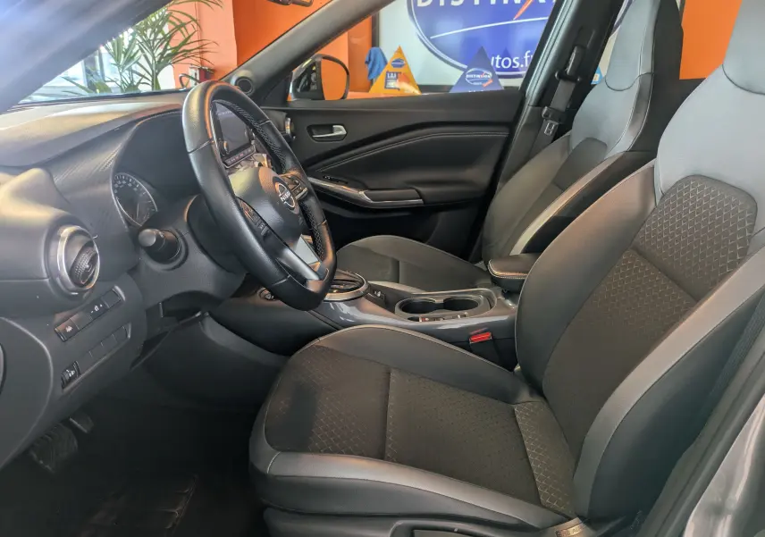 Intérieur avant du Nissan Juke 2024 gris, vue côté conducteur montrant sièges en cuir gris et tableau de bord moderne.