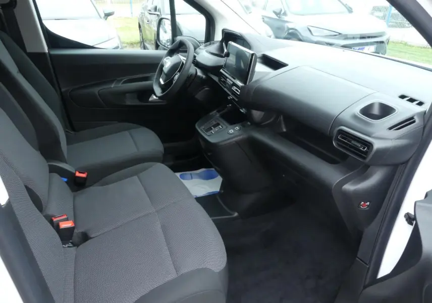 Intérieur du Peugeot Partner XL 2025 vu côté conducteur, sièges tissu gris et tableau de bord noir moderne.