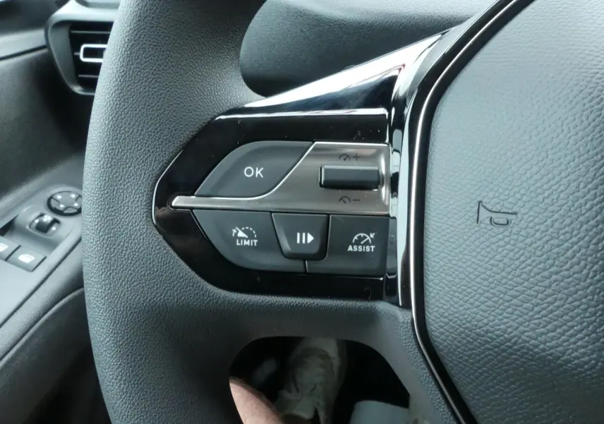 Gros plan sur le volant multifonctions noir du Peugeot Partner 2025 avec commandes de régulateur et limiteur de vitesse.