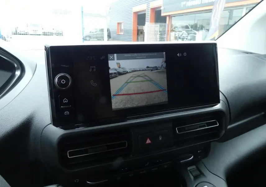 Écran tactile 10 pouces affichant la caméra de recul dans l'habitacle du Peugeot Partner blanc, vue de face.