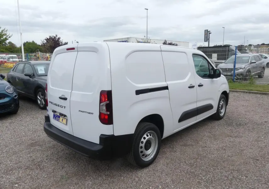 Vue 3/4 arrière droite du Peugeot Partner blanc avec portes arrière battantes et protections latérales noires.