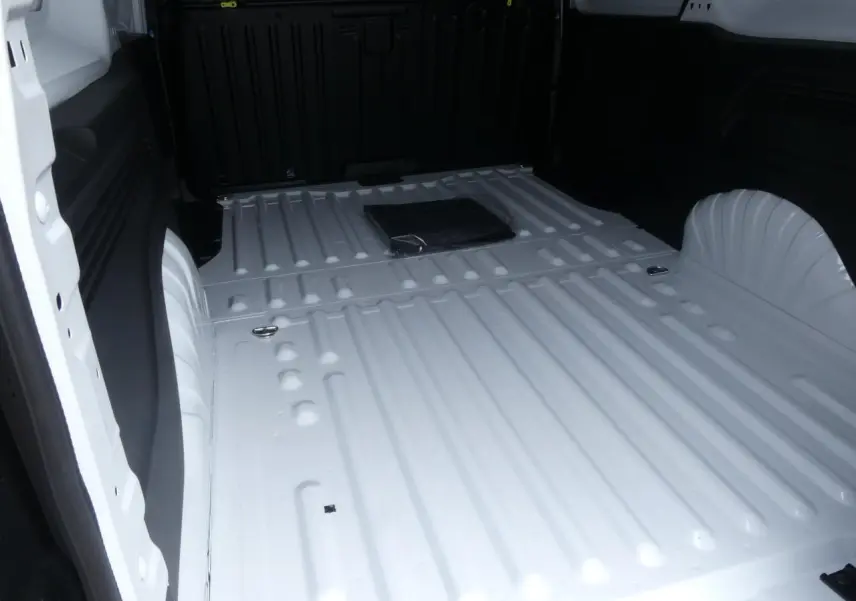 Vue intérieure du compartiment de chargement blanc du Peugeot Partner XL 2025, avec plancher métallique et anneaux d'arrimage.