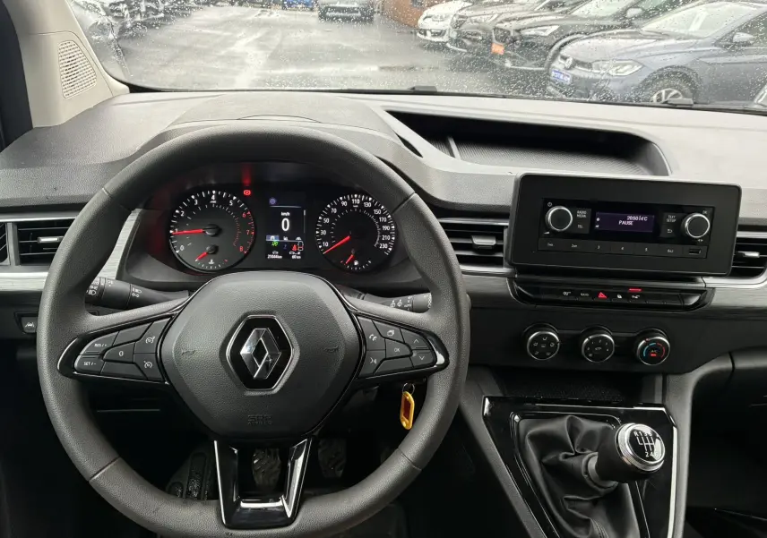 Vue intérieure centrée sur le volant noir et le tableau de bord du Renault Kangoo blanc 2024 avec boîte manuelle et écran multimédia.