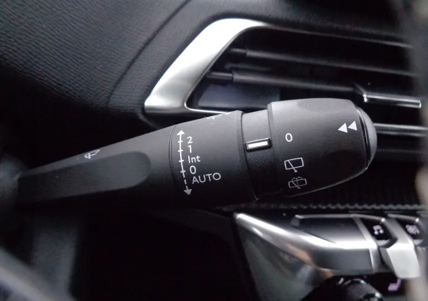 Gros plan sur la manette d'essuie-glace du Peugeot 3008 gris Artense, avec détails des réglages et aérateurs noirs.