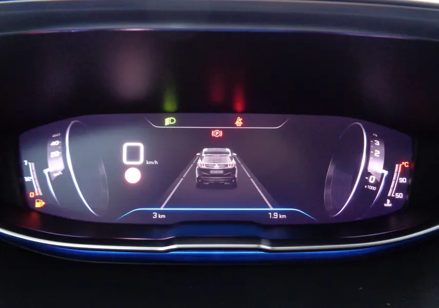 Tableau de bord numérique du Peugeot 3008 2023 affichant la vitesse à 0 km/h et un véhicule gris artense metal en vue arrière.