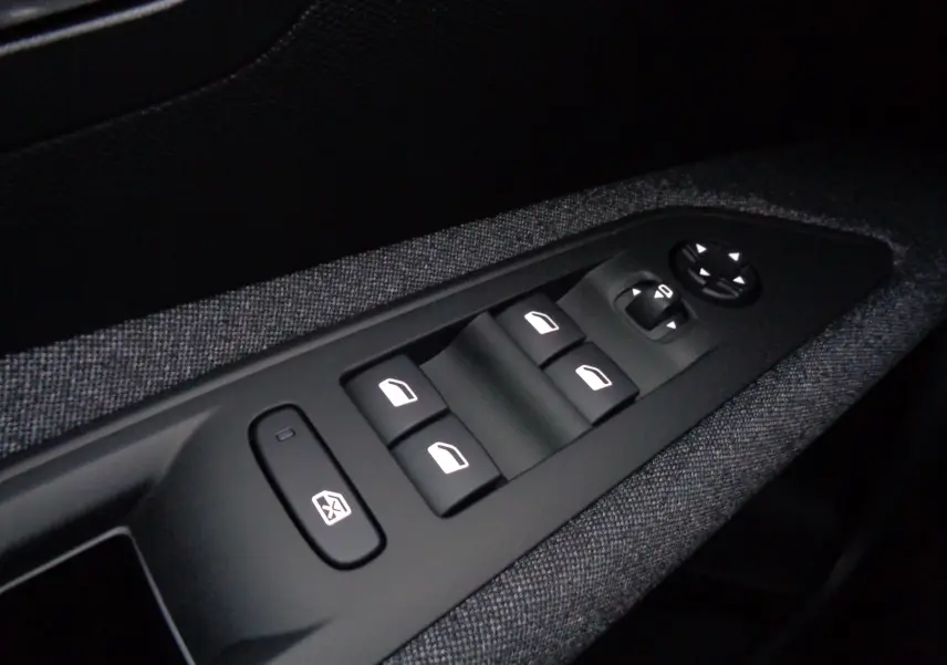 Gros plan sur les commandes des vitres électriques et rétroviseurs côté conducteur du Peugeot 3008 gris Artense 2023.