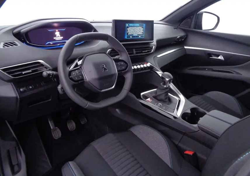 Intérieur avant droit du Peugeot 3008 2023 gris avec volant compact, écran tactile et levier de vitesse manuel.