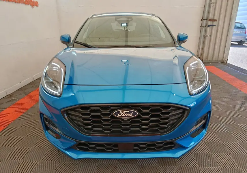 Vue frontale d'une Ford Puma bleu vif avec calandre noire hexagonale et phares LED distinctifs.