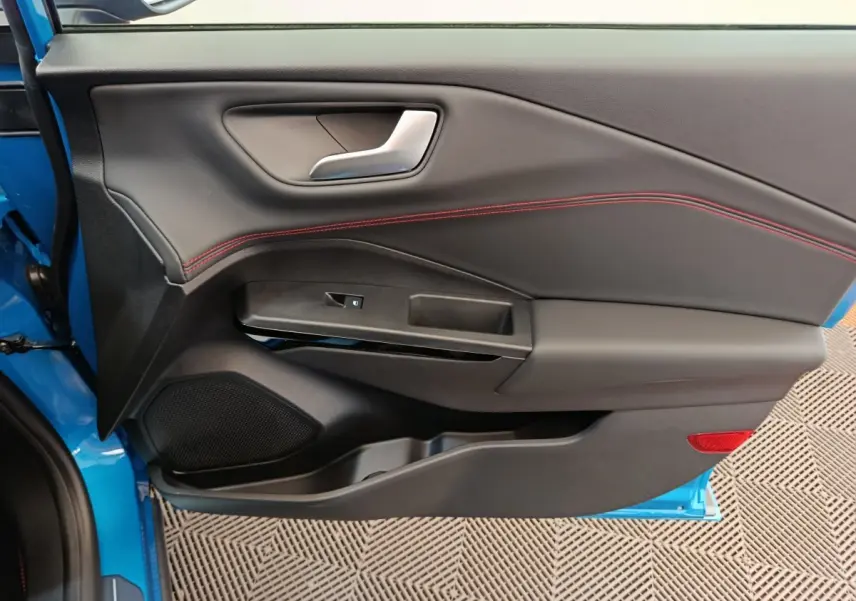 Porte intérieure côté gauche du Ford Puma bleu 2025, avec surpiqûres rouges et commande de vitre intégrée.