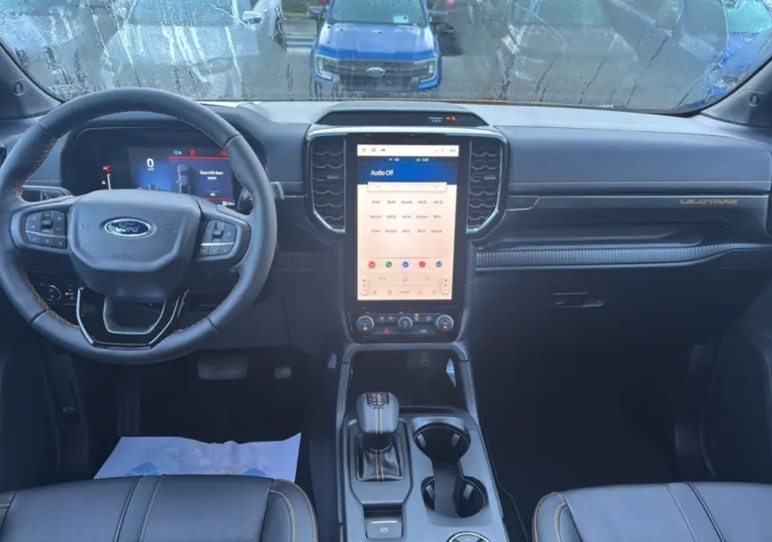 Vue intérieure avant du Ford Ranger 2.3 PHEV Wildtrak Plus 2025 avec tableau de bord numérique et écran tactile central.