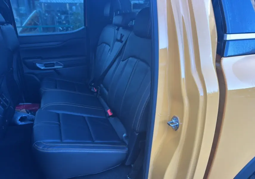 Vue intérieure côté gauche sur les sièges arrière en cuir noir du Ford Ranger 2025 Cyber orange Wildtrak Plus hybride.