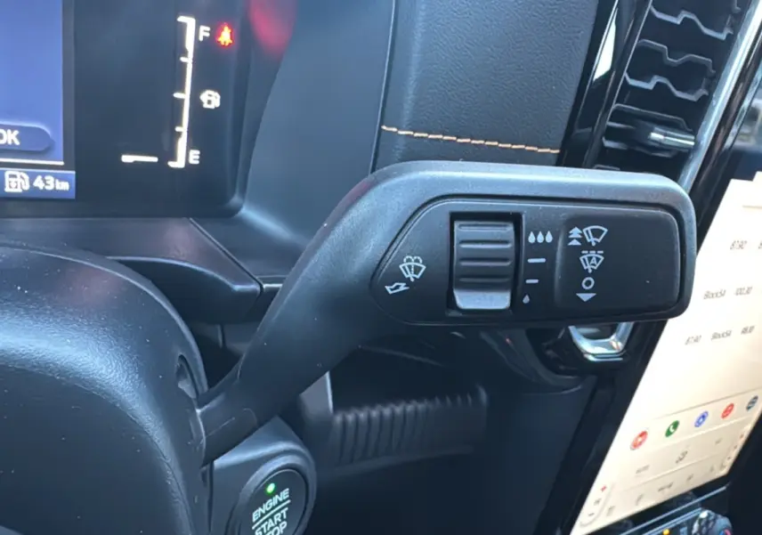 Gros plan sur la commande d’essuie-glace du Ford Ranger 2.3 PHEV 281 Wildtrak Plus 2025, intérieur noir avec surpiqûres orange.
