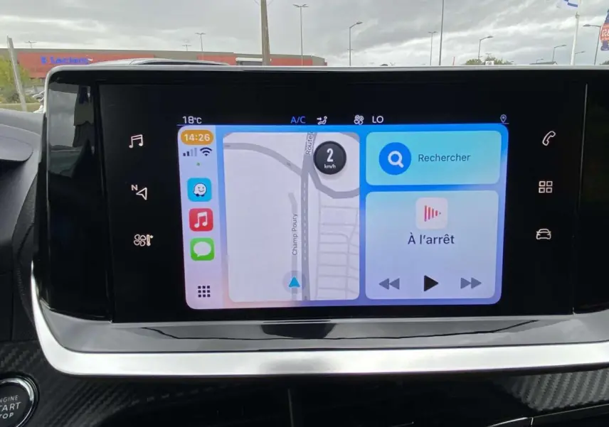 Écran tactile central affichant la navigation et commandes multimédia dans le Peugeot 208 bleu, vue intérieure frontale.