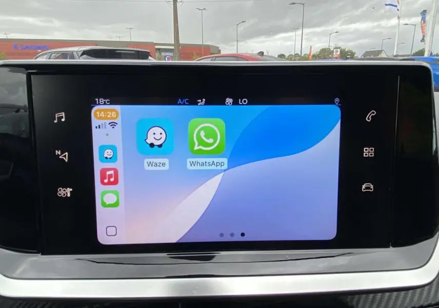 Écran tactile 7 pouces du tableau de bord de la Peugeot 208 1.2i PureTech 2020 affichant Waze et WhatsApp.