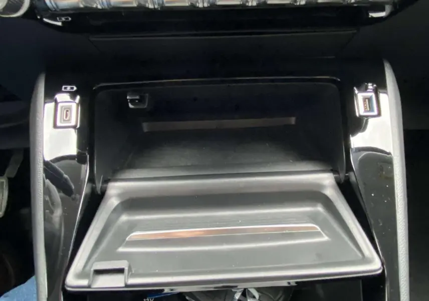 Gros plan sur la console centrale noire du Peugeot 208 1.2i PureTech 2020 avec compartiment ouvert et ports USB visibles.