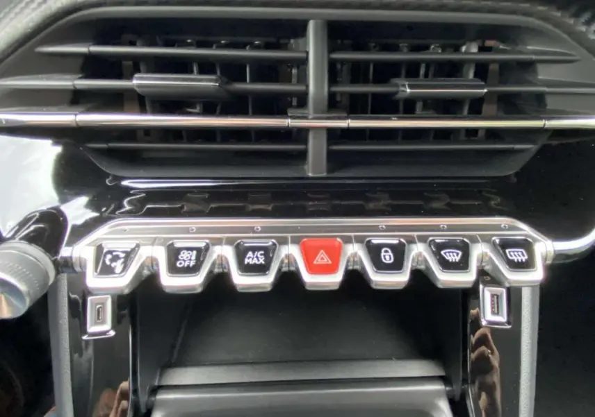 Gros plan sur la console centrale du Peugeot 208 bleu 2020, montrant les commandes climatisation et boutons fonctionnels.