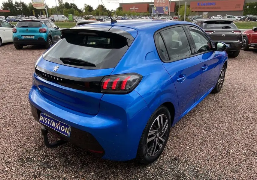 PEUGEOT 208 bleu vue 3/4 arrière droit, avec feux arrière allumés et jantes alliage 16 pouces diamantées.