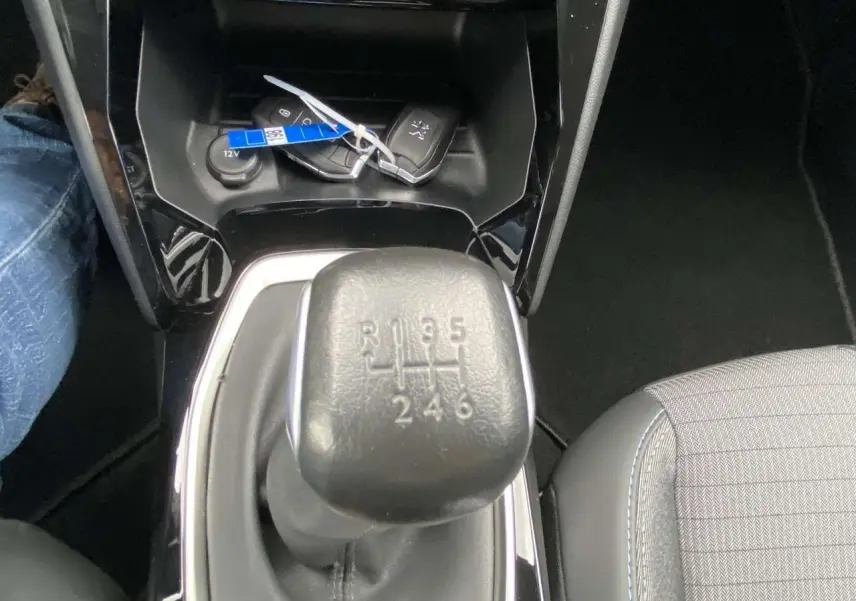 Gros plan sur le levier de vitesses manuel noir de la Peugeot 208 1.2i PureTech, avec clés posées à côté.