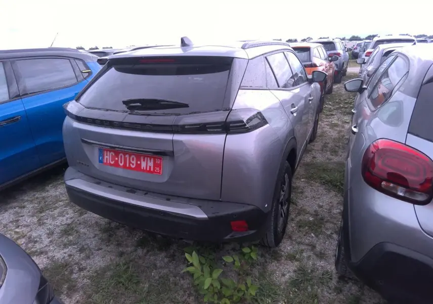 Vue 3/4 arrière d'un Peugeot 2008 gris clair avec toit noir et feux arrière LED en forme de griffes.