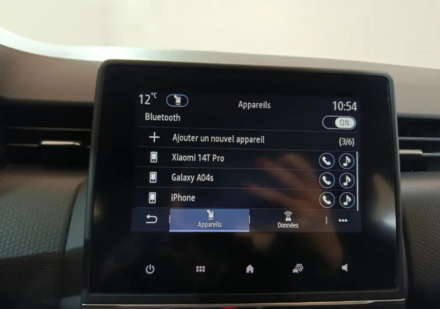 Écran tactile central affichant menu Bluetooth dans l'habitacle d'une Renault Clio Business blanc, vue frontale rapprochée.
