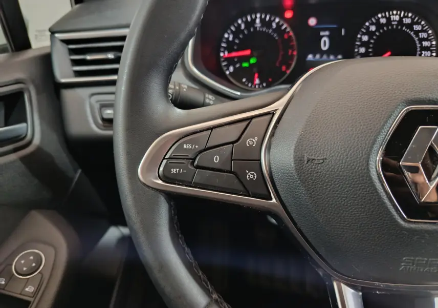 Gros plan sur le volant cuir noir de la Renault Clio Business TCe 90 2021 avec commandes intégrées et tableau de bord éclairé.