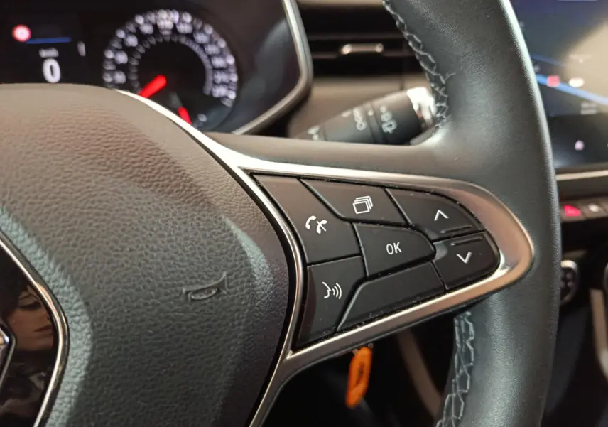 Gros plan sur le volant cuir noir de la Renault Clio Business TCe 90 avec commandes multifonctions et tableau de bord partiellement visible.