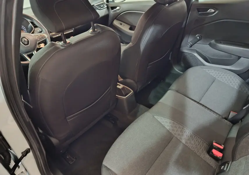 Vue intérieure arrière côté droit de la Renault Clio Business TCe 90 blanche, sièges tissu noir et tableau de bord partiel visible.