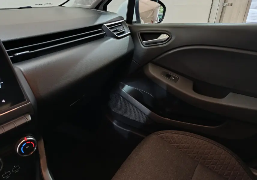 Intérieur côté passager de la Renault Clio Business blanc, montrant tableau de bord et porte avec commande vitre électrique.