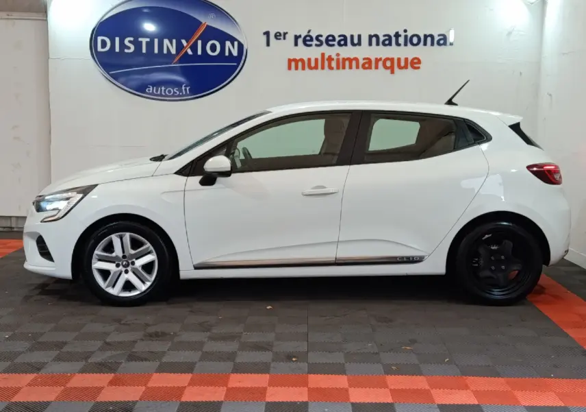 Profil côté gauche d'une Renault Clio Business TCe 90 blanche 2021 avec jantes avant argent et arrière noires, en intérieur showroom.