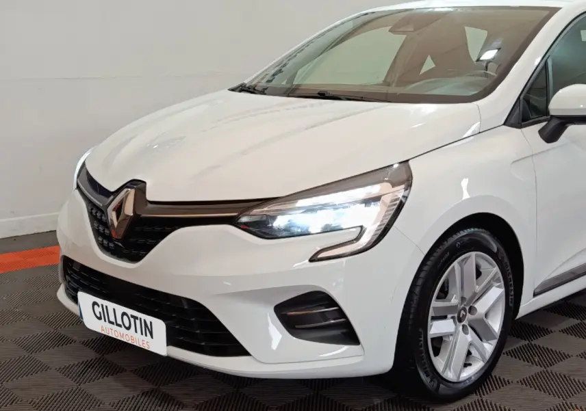 Renault Clio Business TCe 90 blanc vue 3/4 avant droit, feux LED allumés et jantes alliage visibles.