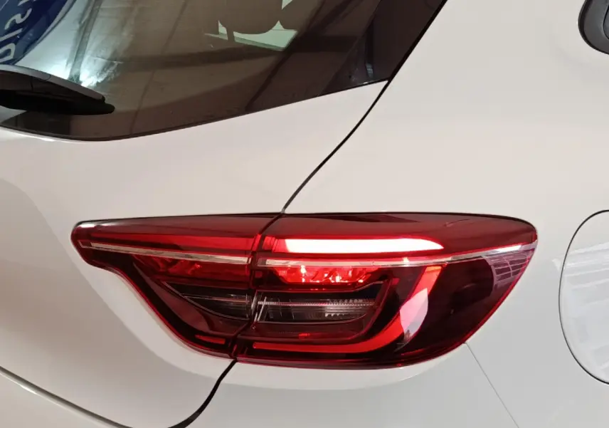 Gros plan sur le feu arrière droit rouge d'une Renault Clio Business blanche de 2021, avec la portière visible.