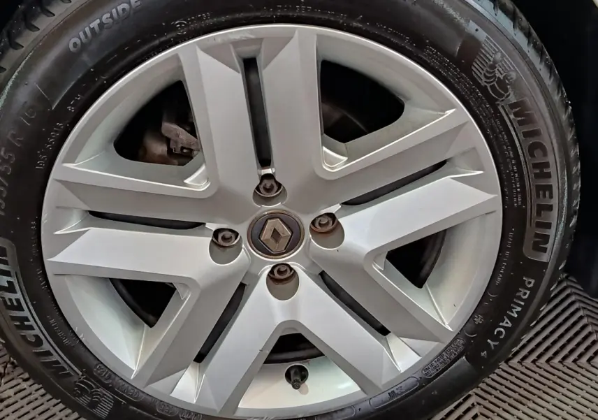 Gros plan sur la jante alliage argentée avec logo Renault au centre d'une Renault Clio blanche.