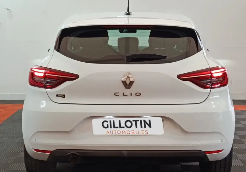 Vue arrière d'une Renault Clio blanche 2021 avec feux LED et logo centré sur un fond intérieur neutre.