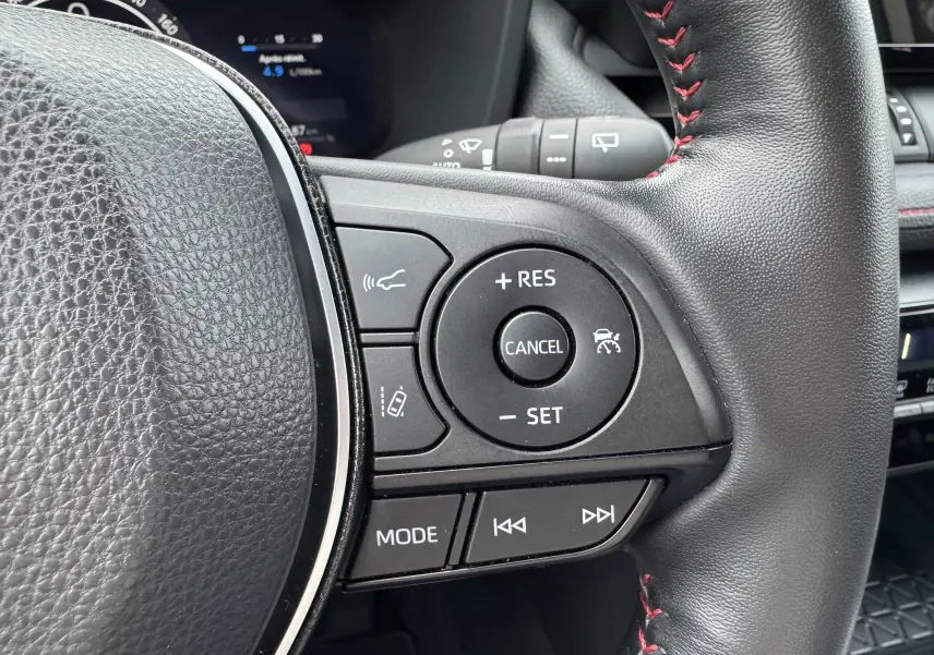 Gros plan sur les commandes du volant noir avec surpiqûres rouges du Suzuki Across hybride rechargeable 2023.