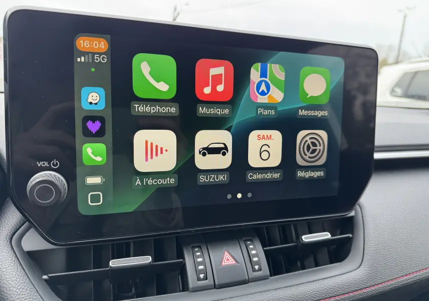 Écran tactile central du Suzuki Across 2023 affichant les applications connectées avec commandes de climatisation en dessous.