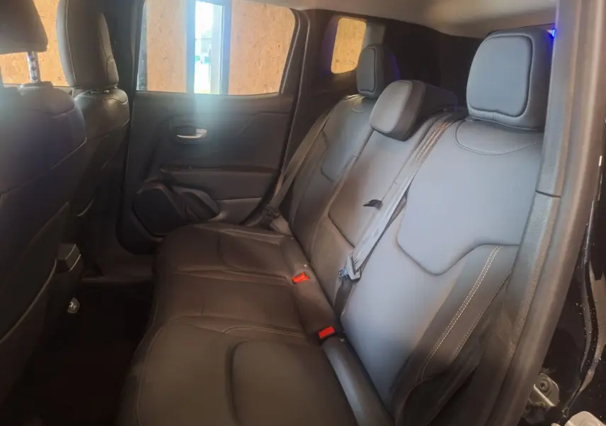 Vue intérieure côté droit des sièges arrière en cuir noir du Jeep Renegade 2024 hybride, avec ceintures de sécurité visibles.