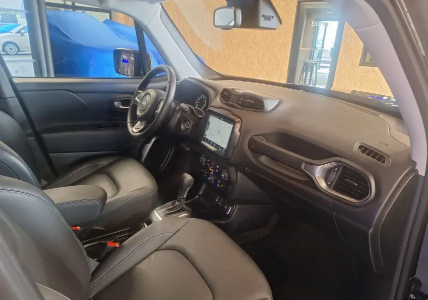 Intérieur noir cuir de la Jeep Renegade 2024, vue côté conducteur avec tableau de bord et écran tactile central.