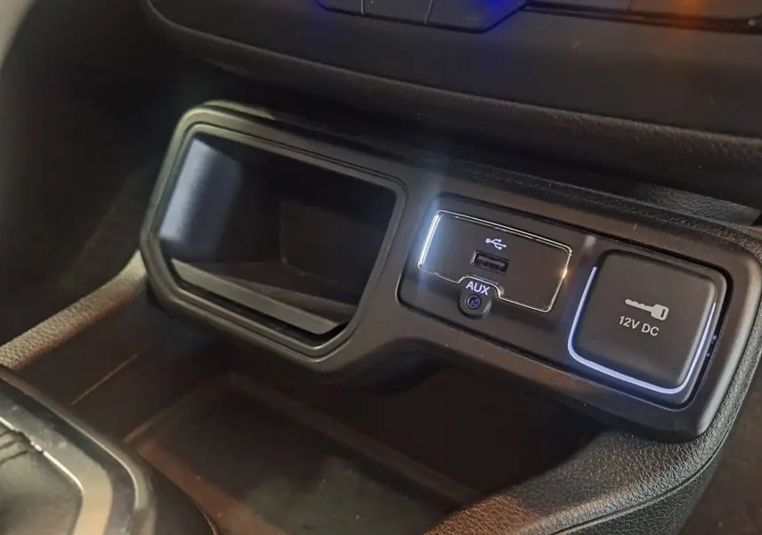 Gros plan sur la console centrale noire du Jeep Renegade 2024, montrant les ports USB, AUX et prise 12V DC.