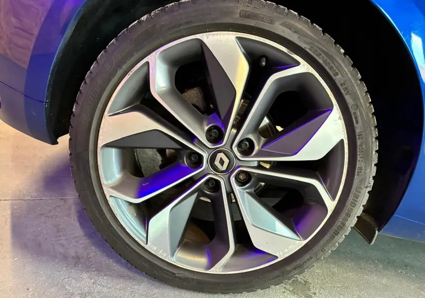 Gros plan sur la jante alliage grise à design moderne de la Renault Mégane bleu visible au-dessus du pneu.